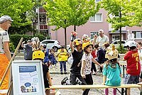 Kinder und Erwachsene auf einem Platz vor einem Wohngebäude bei einem Mitmach-Theaterstück 