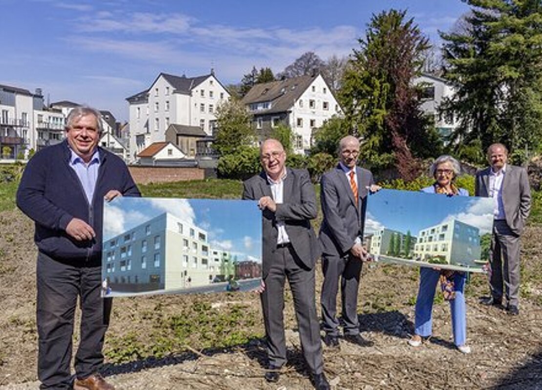 Fünf Personen präsentieren auf einer Freifläche im Außenbereich zwei großformatige Visualisierungen des Neubauvorhabens an der Ringstraße in Essen-Kettwig.