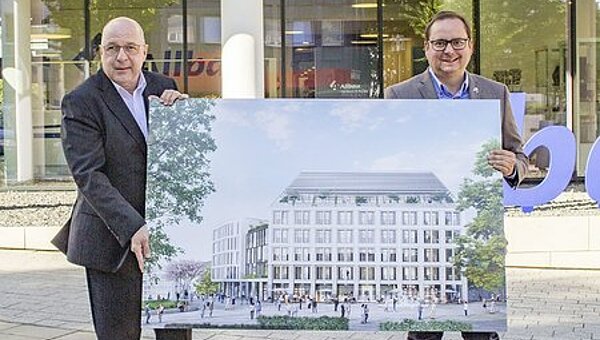 Allbau-Geschäftsführer Dirk Miklikowski (links) und der Essener Oberbürgermeister Thomas Kufen halten eine großformatige Abbildung des geplanten Neubaus am Essener Weberplatz. 