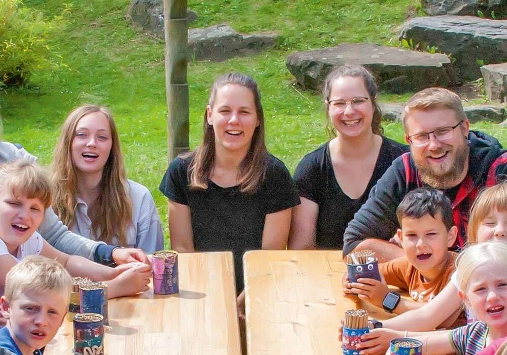 Allbau-Kinderbeauftragte und andere Erwachsene mit Kindern draußen am Tisch